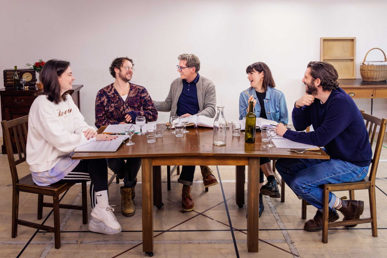 Farewell Mr Haffman Rehearsals with the cast sitting, chatting and laughing at a large dining table on the set of the production