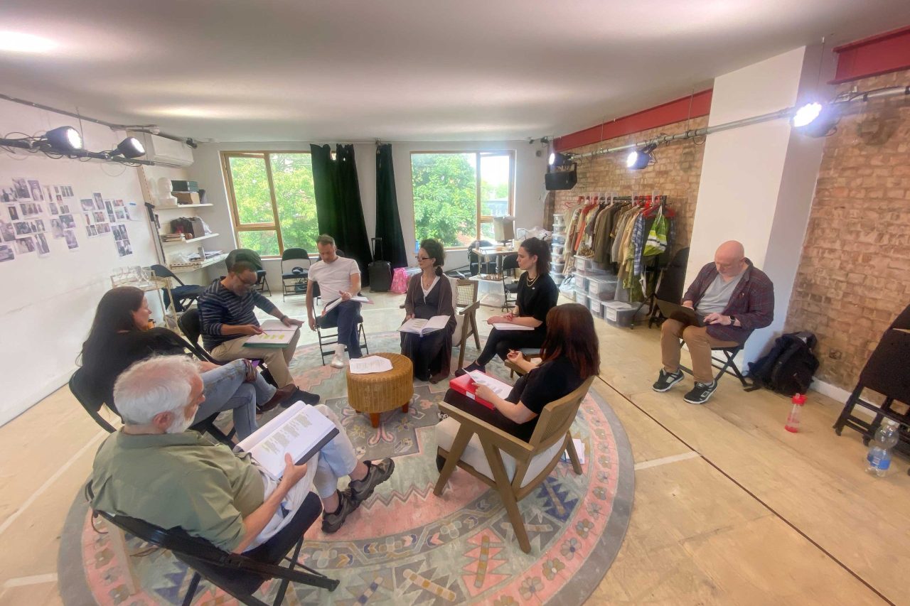 Morris Space, with 8 people sitting on chairs with scripts reheasring a play