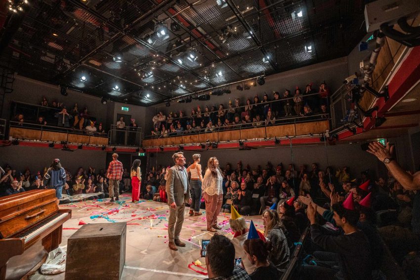 A full audience in Park 200 cheering and clapping as the cast look up about to bow.