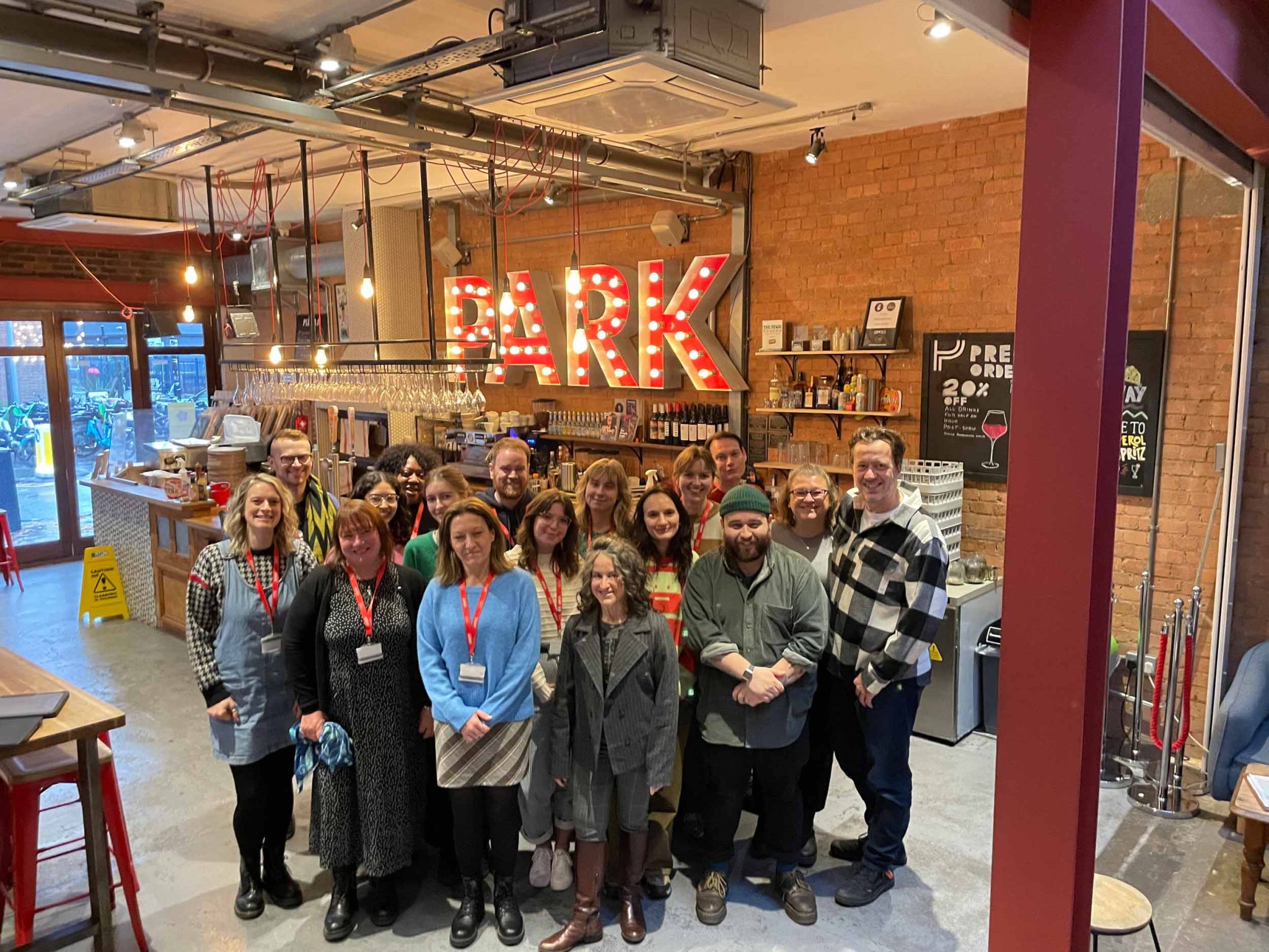Arcola Staff stand smiling in the downstairs bar with the park sign in the background