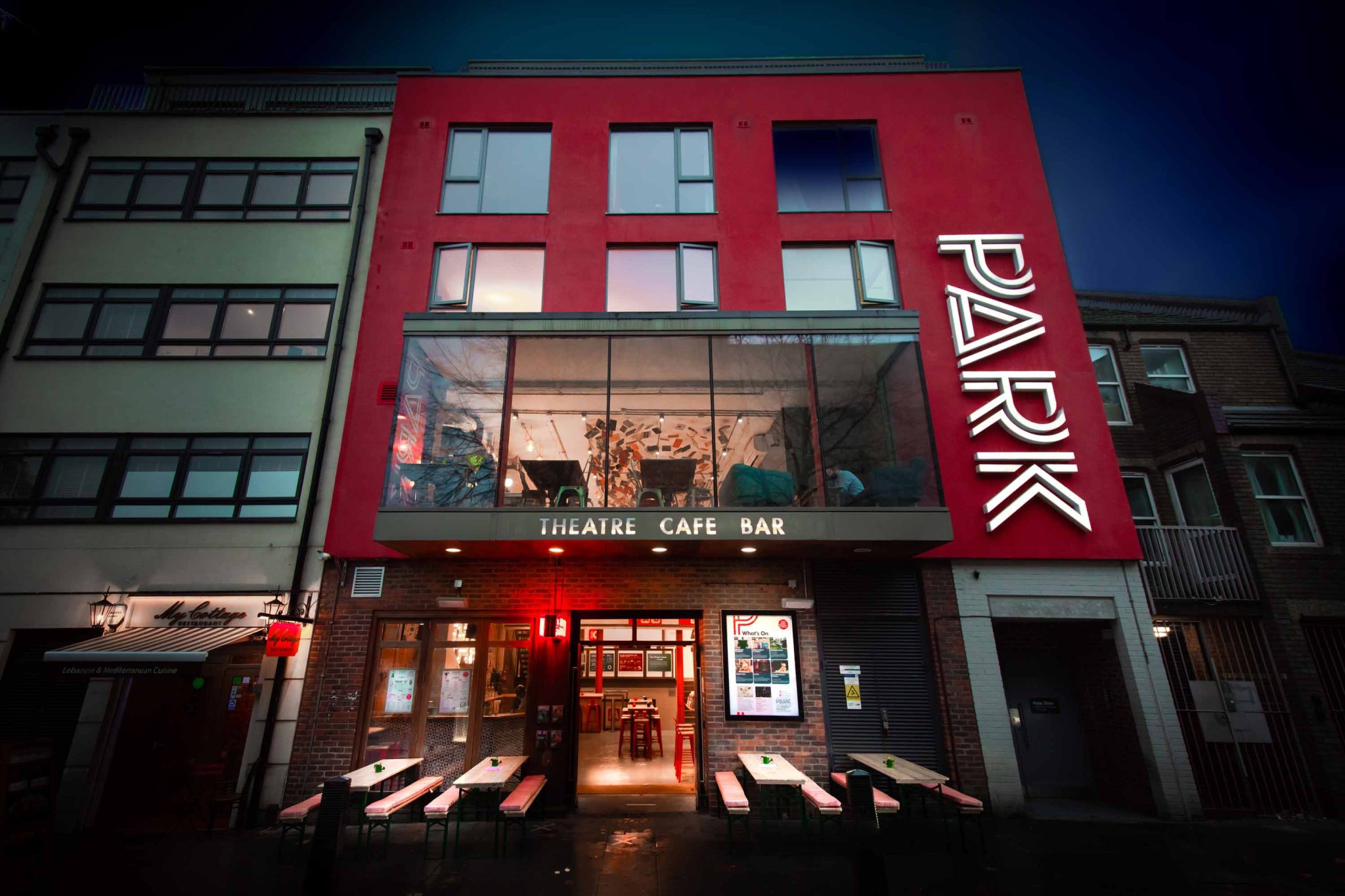 Park Theatre Building, Park logo on the side of the building and a large window on the second floor of the building, underneath the window it says Theatre, Cafe and Bar with outside seating at the front of the building on the ground floor